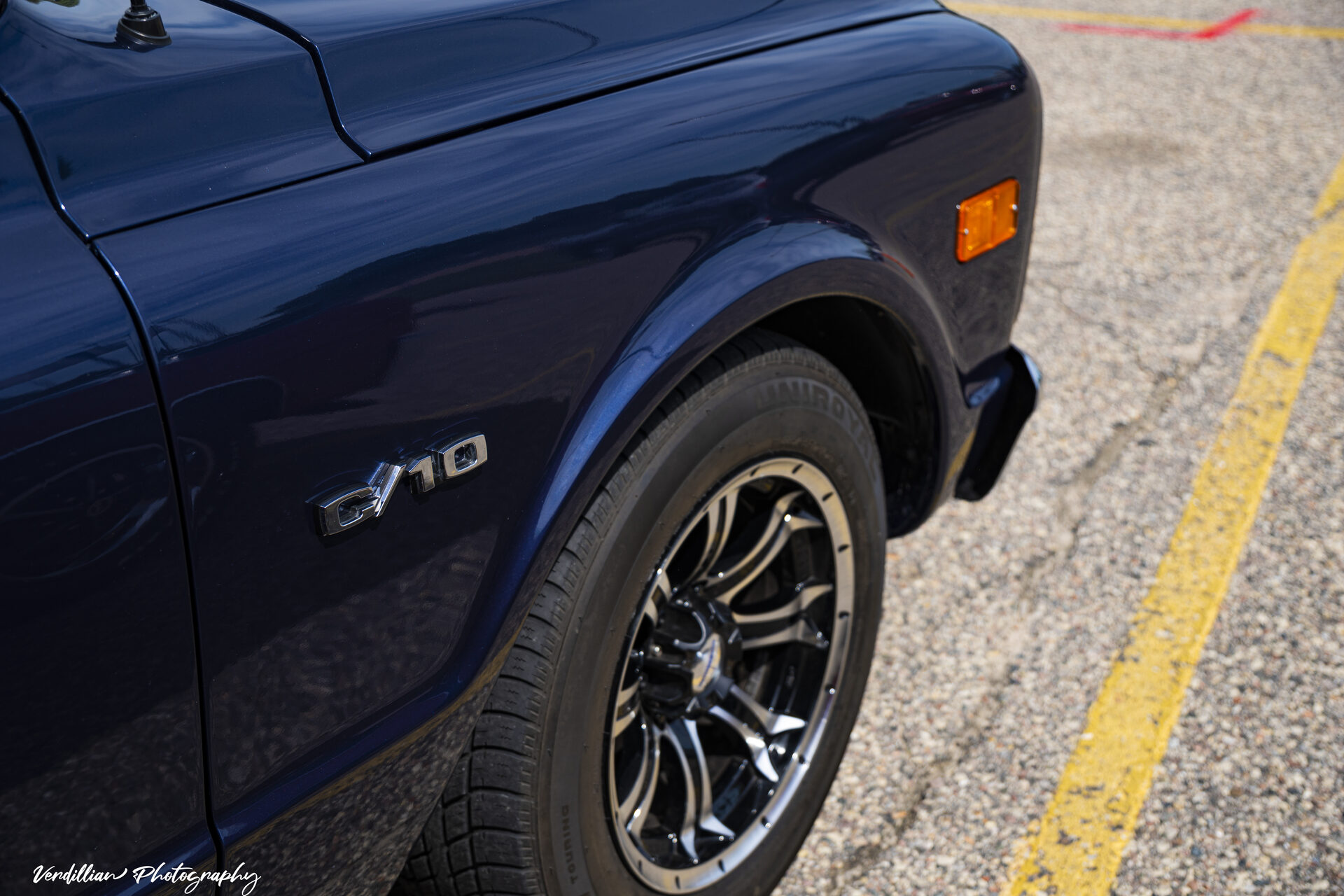 Close-up of a dark blue Chevrolet C/10's fender badge and wheel